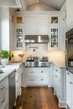 a kitchen with white cabinets and wood floors