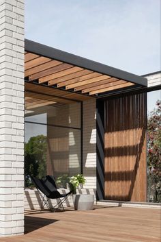 a black chair sitting on top of a wooden floor next to a white brick building