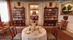 there is a table in the room with many bookshelves and chairs around it