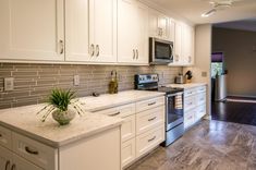 a kitchen with white cabinets and marble counter tops