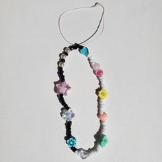 a necklace with beads and charms hanging from it's side on a white surface