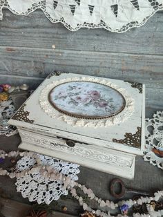 an old white box sitting on top of a table next to doily and lace