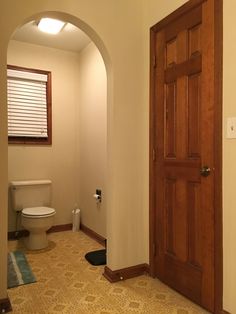 an open door leading to a bathroom with a toilet in the corner and a rug on the floor