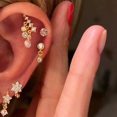 a close up of a person's hand holding an ear with three different types of piercings on it