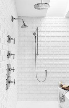 a bathroom with white brick walls and an open shower head in the corner, along with two faucets on either side of the bathtub