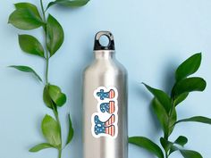 a stainless steel water bottle with an american flag sticker on it next to some green leaves