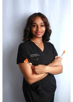 a woman in scrubs is posing with her arms crossed