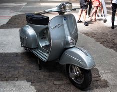 a scooter is parked on the side of the road while people walk by