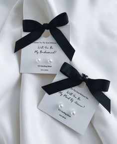 two white cards with black ribbons tied to them