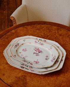 four plates sitting on top of a wooden table next to a white chair in a room