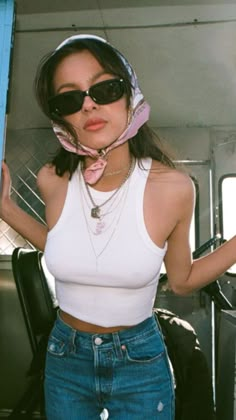 a woman wearing sunglasses and a bandana standing in the back of a truck