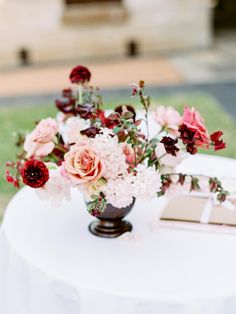 a vase filled with flowers sitting on top of a white table covered in cloths