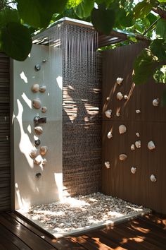 an outdoor shower with shells on the wall and wood flooring, surrounded by greenery