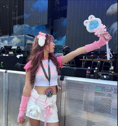 a woman in pink and white outfit holding up her hairbrush at a music festival