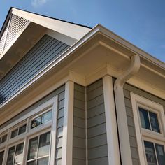 the corner of a house with two windows on each side and a roof that has a metal gutter attached to it