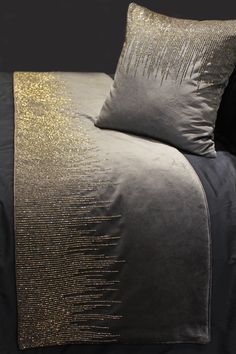 a bed with two pillows on top of it and gold sequins in the middle