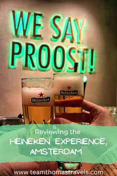 two glasses of beer in front of a neon sign that says we say proost reviewing the heineken experience, amsterdam