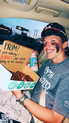 a man sitting in the back seat of a car holding a box of donuts