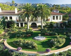 an aerial view of a large home surrounded by greenery and palm trees with mountains in the background