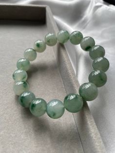 Item Code: JBD226001  Burmese Grade A Jadeite Jade Carved out from a single stone, this piece of jadeite bead bracelet is one of the uncommon ones in the market. Great translucency due to it being the icy type jadeite. One notable feature is the fine texture of each of the beads. The color of this bead bracelet varies according to the lighting of the surrounding but its true color which can be seen under natural lighting as taken in the last picture is misty green. Each of the beads has green floating flowers which is an added value to the piece. All our photos were taken under natural light settings to showcase the true essence and colours of the pieces. We condemn the uses of any photo editing softwares to alter the colours of the pictures taken. We try to capture the true colours of the Elegant Green Agate Crystal Bracelet, Elegant Jade Crystal Bracelet With Round Beads, Green Agate Round Crystal Bracelet, Green Agate Hand-strung Crystal Bracelet, Green Jade Gemstone Beads Bracelets, Green Jade Gemstone Beaded Bracelets, Jade Gemstone Crystal Bracelet, Round Jade Crystal Bracelet With Gemstone, Jade Crystal Bracelet With Natural Stones