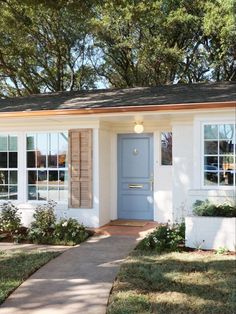 a small white house with blue doors and shutters on the front door is shown