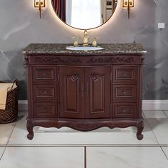 a bathroom vanity with an oval mirror above it and marble counter top in the middle