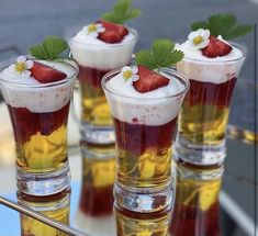 four glasses filled with dessert sitting on top of a table