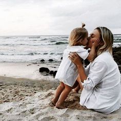 a mother and daughter kissing on the beach