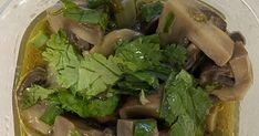 a clear bowl filled with mushrooms and greens