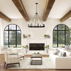 a living room filled with white furniture and large windowed windows next to a fire place