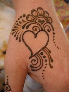 a woman's hand with a henna tattoo on it and a heart in the middle