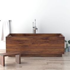 a wooden bathtub sitting on top of a hard wood floor next to a white wall