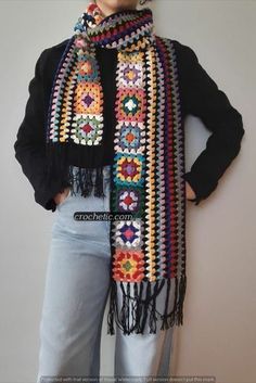 a woman is wearing a multicolored crocheted scarf