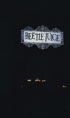 a street sign lit up at night with the word beetlele juice on it's side