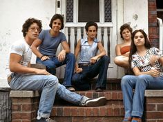 four young people sitting on the steps of a house with their feet up in front of them