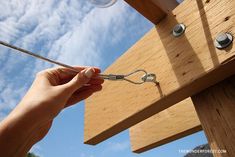 a person is holding some scissors near a piece of wood