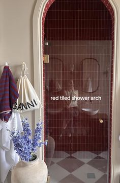 a red tiled shower area with blue flowers in a vase and an umbrella hanging on the wall