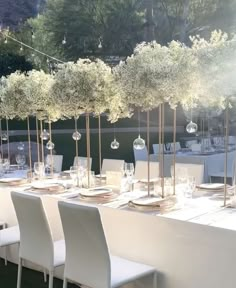 a long table set with white chairs and place settings