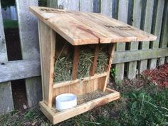 a wooden bird feeder with hay in it