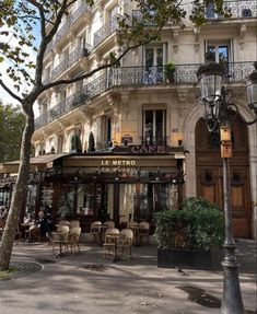 an empty street with tables and chairs in front of a building that has balconies on it