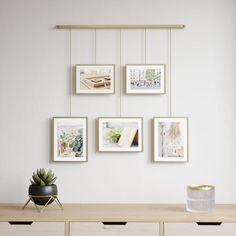 a wooden table topped with a potted plant next to pictures hanging on the wall