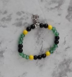 Represent your Caribbean heritage with this lovely bracelet made in Jamaica flag colors.  Choose the love charm or the crown charm when you make your selection or purchase both. Bracelet makes a lovely gift for Christmas, Caribbean festivities or everyday wear.  This stretch bracelet measures  7.5" and will fit most adults.  Materials Antique Tibetan charm and tube bead Glass beads Faceted Beads Green Bracelets With Charms And Round Beads, Green Bangle Charm Bracelet For Jewelry Making, Waist Beads Jamaican, Juneteenth Bracelet Ideas, Jamaican Beaded Jewelry, Jamaica Bracelet, Adjustable Green Charm Bracelet With Lobster Clasp, Jamaican Necklace, Jamaica Flag