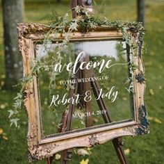 an easel with greenery on it and the words welcome to the wedding