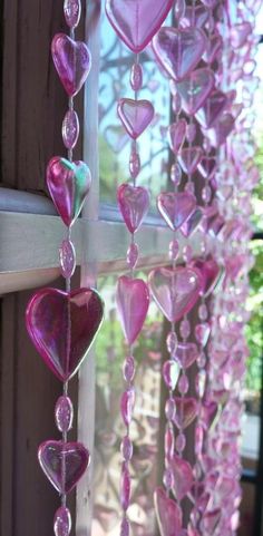 some pink hearts hanging from a window sill