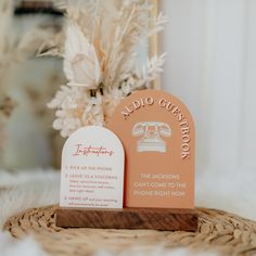 an orange business card sitting on top of a wooden stand next to a white flower