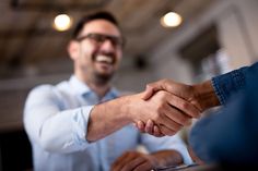 two men shaking hands while sitting at a table