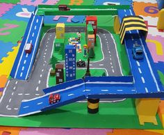 a child's play area with cars and trucks on the road, roads and buildings