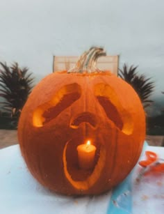 a carved pumpkin sitting on top of a table with a lit candle in its mouth