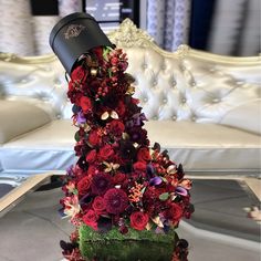 a wine bottle is sitting on top of a flowered display in front of a couch