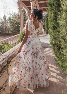 a woman in a floral dress walking down a walkway